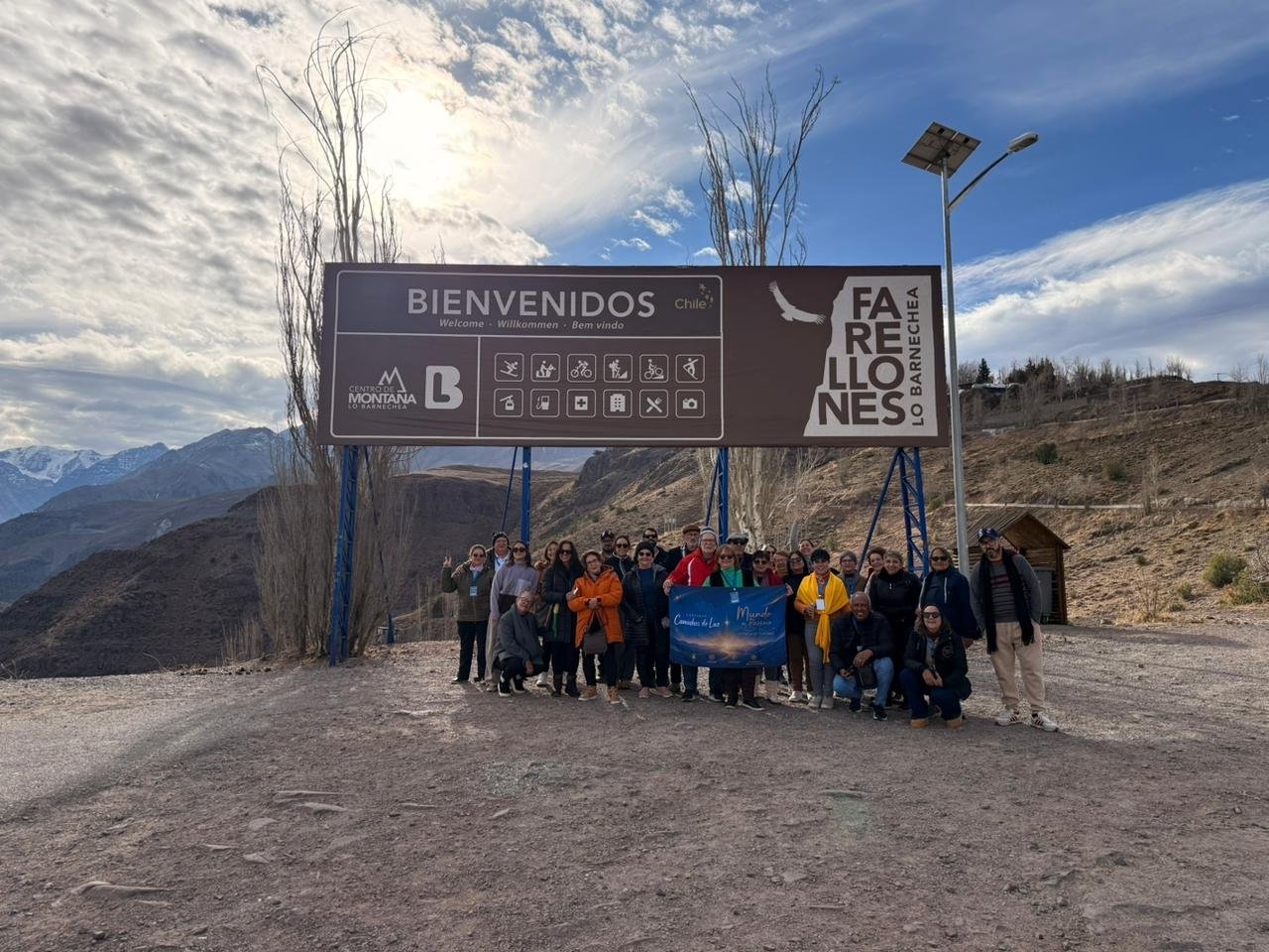 Grupo grande com camiseta azul em paisagem de montanha, luz clara, composição equilibrada