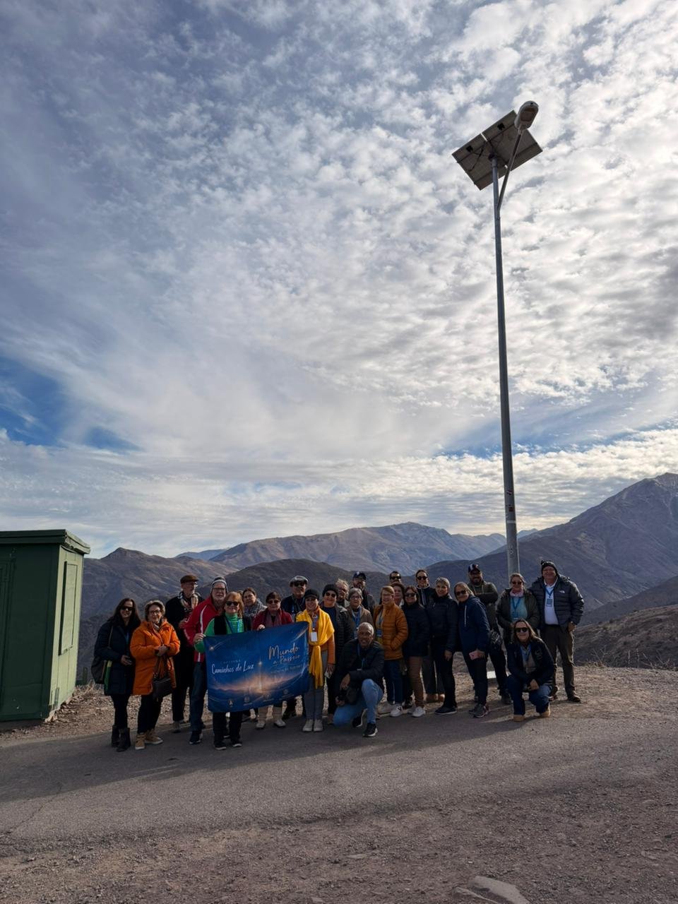 Grupo grande com camiseta azul em planalto montanhoso árido, paisagem e pessoas em harmonia