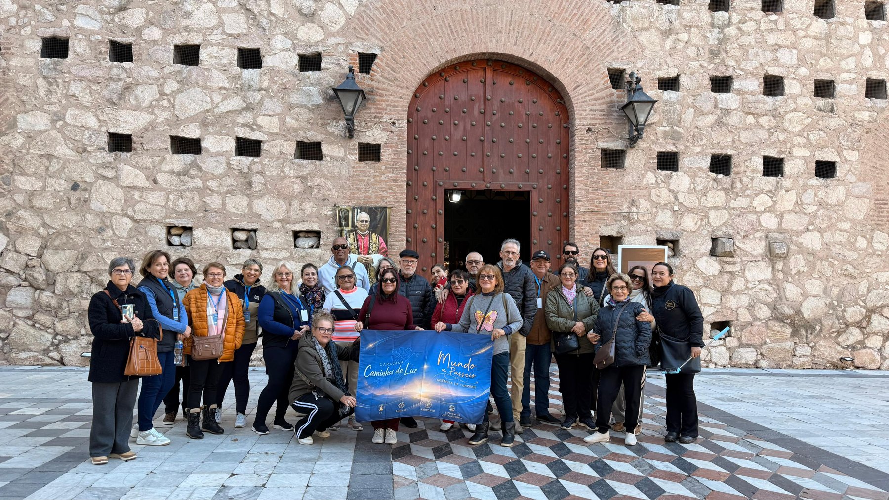 Grupo com bandeira em frente a edifício histórico, composição simétrica e clara
