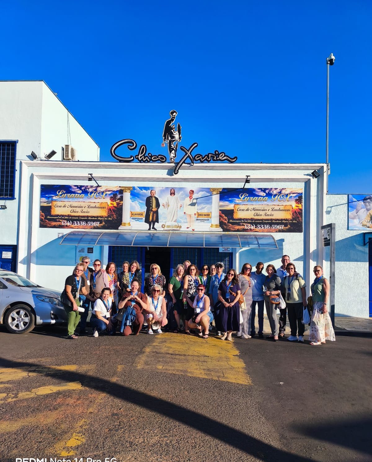 Grupo com ônibus azul ao fundo em cenário aberto, boa profundidade de campo