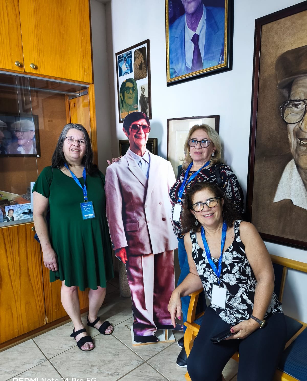 Grupo grande em interior decorado com fotos e quadros, pessoas contentes