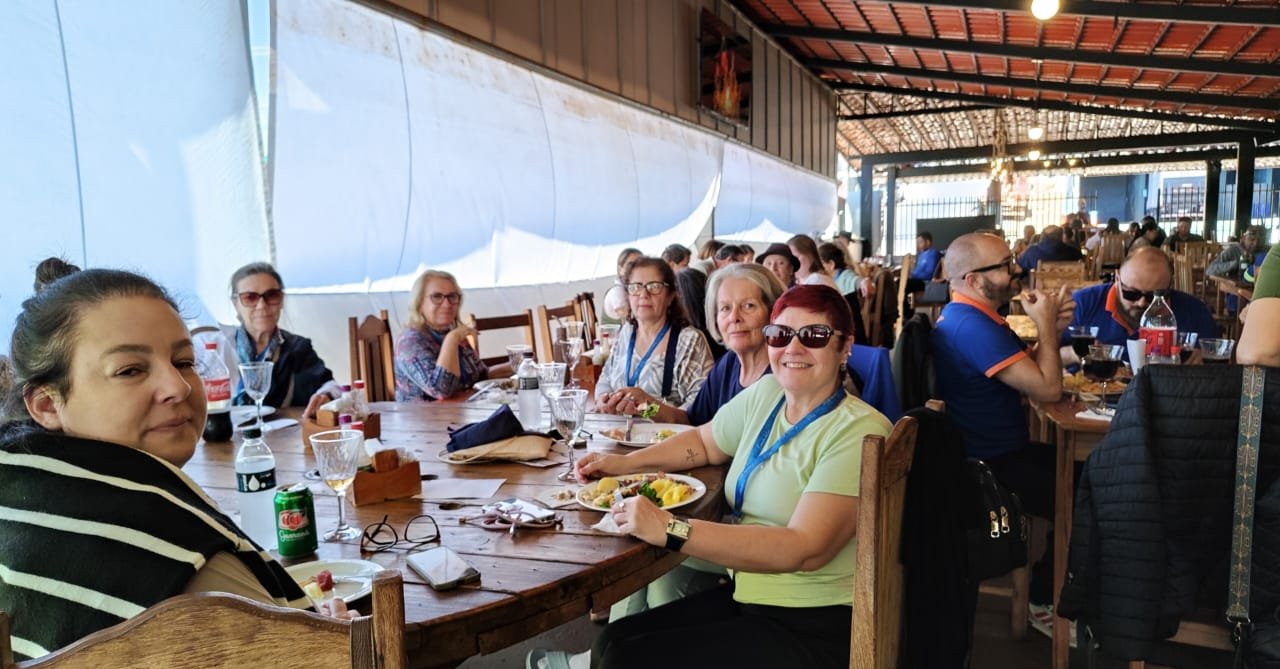 Mesa grande de refeição coletiva com grupo em ambiente de refeitório aconchegante