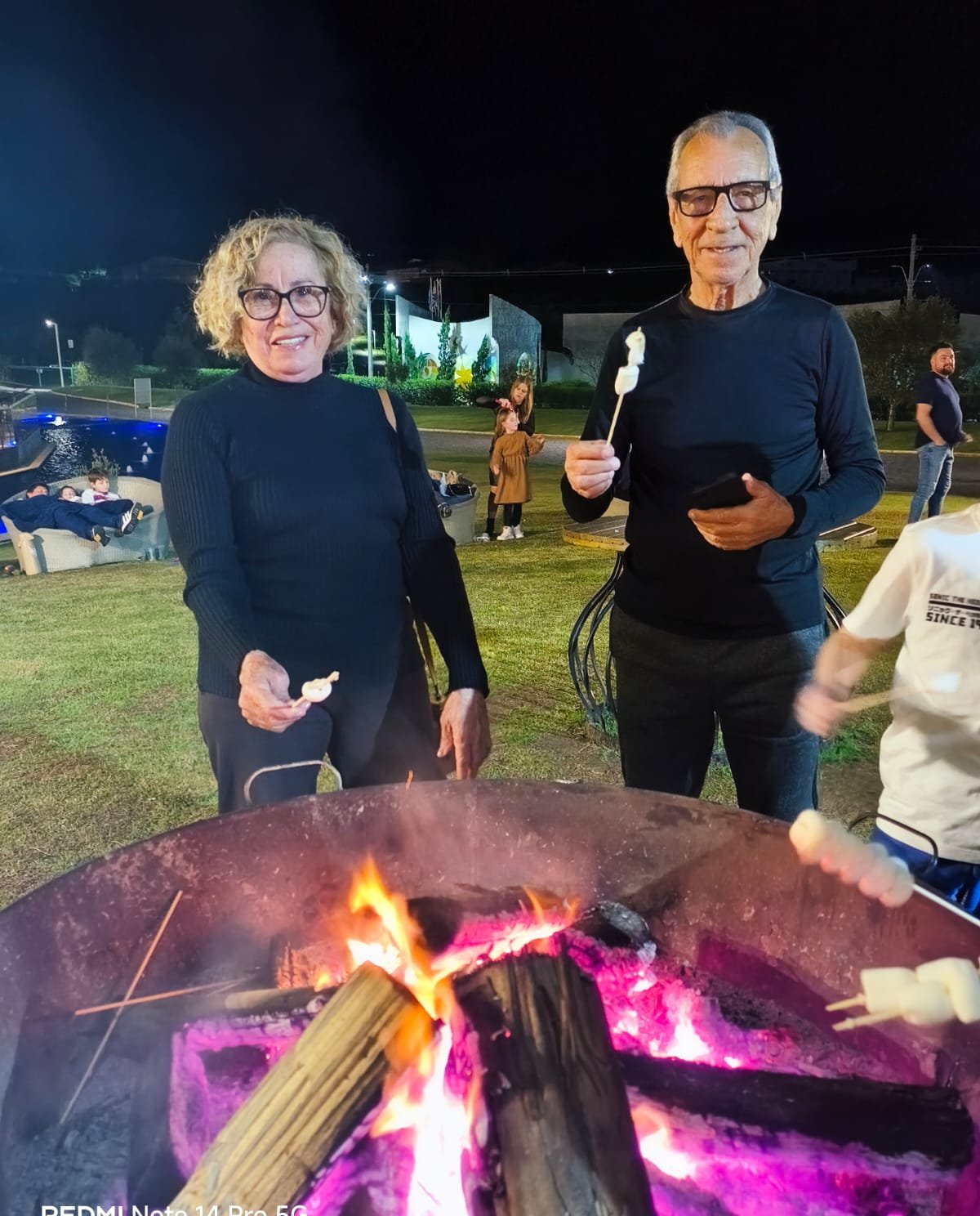 Casal em momento aconchego perto de fogueira acesa à noite