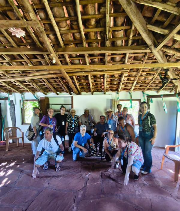 Grupo reunido sob estrutura de madeira e sape em espaco rustico