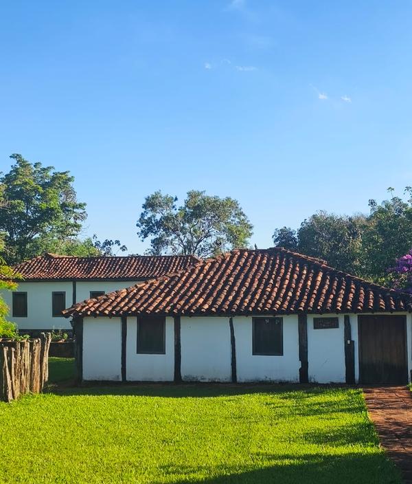 Fachada de casarao colonial branco com telhado de barro e jardim