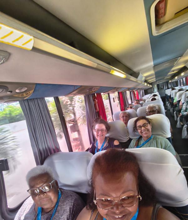 Passageiras sorrindo sentadas lado a lado durante trajeto de onibus