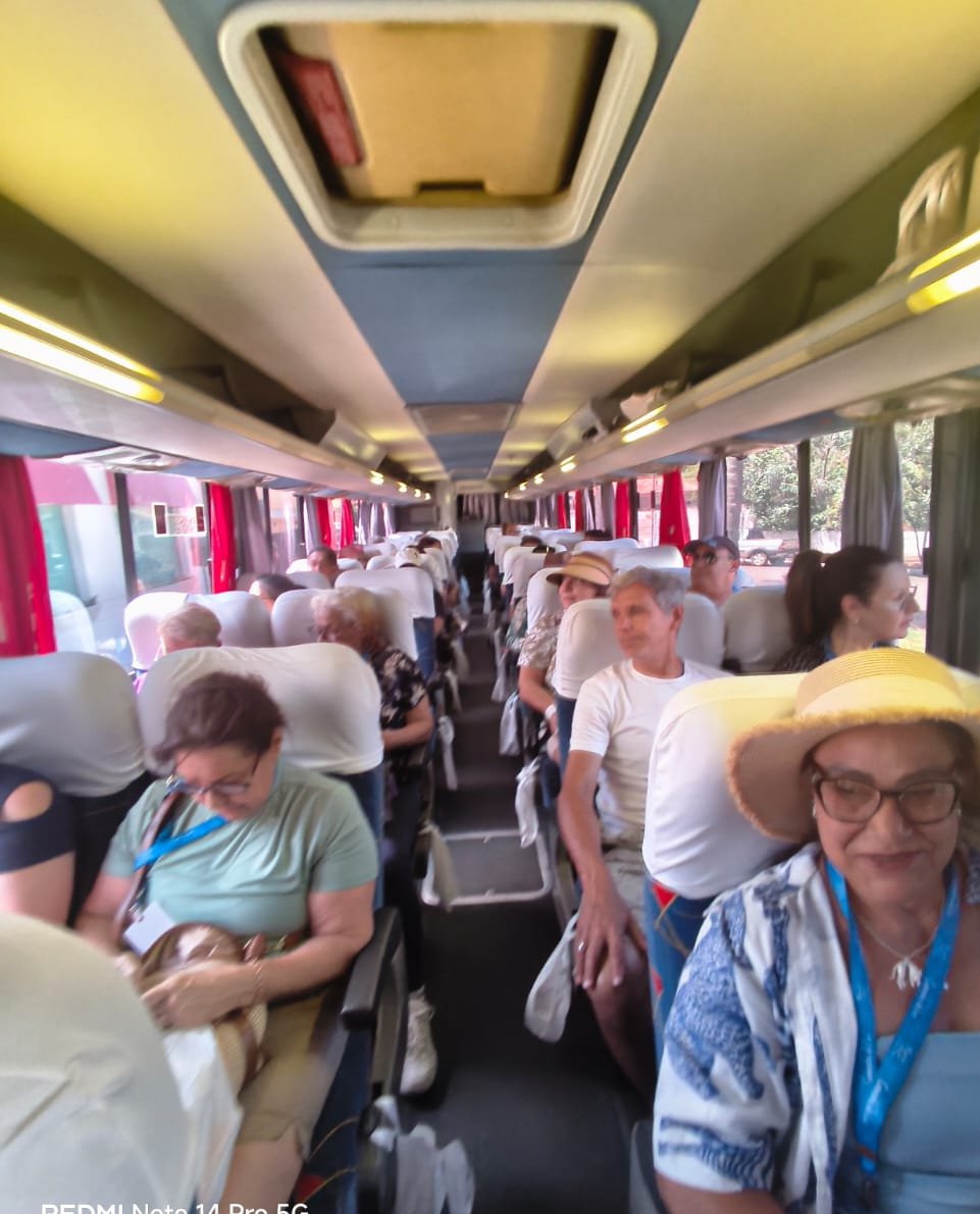 Interior do ônibus com passageiros em assentos, grupo viajando, experiência de viagem