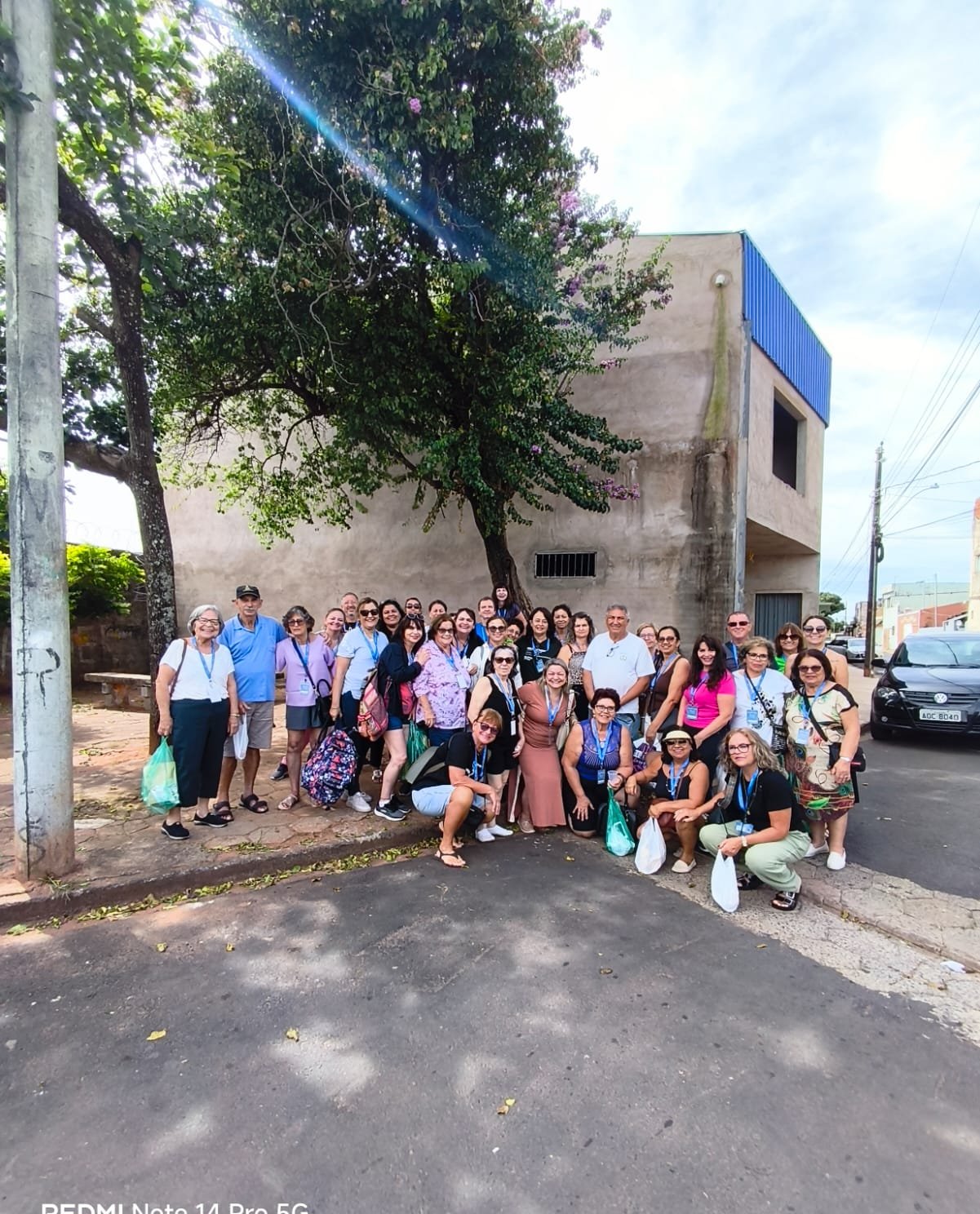 Grupo reunido em calçada em frente a residência histórica colonial