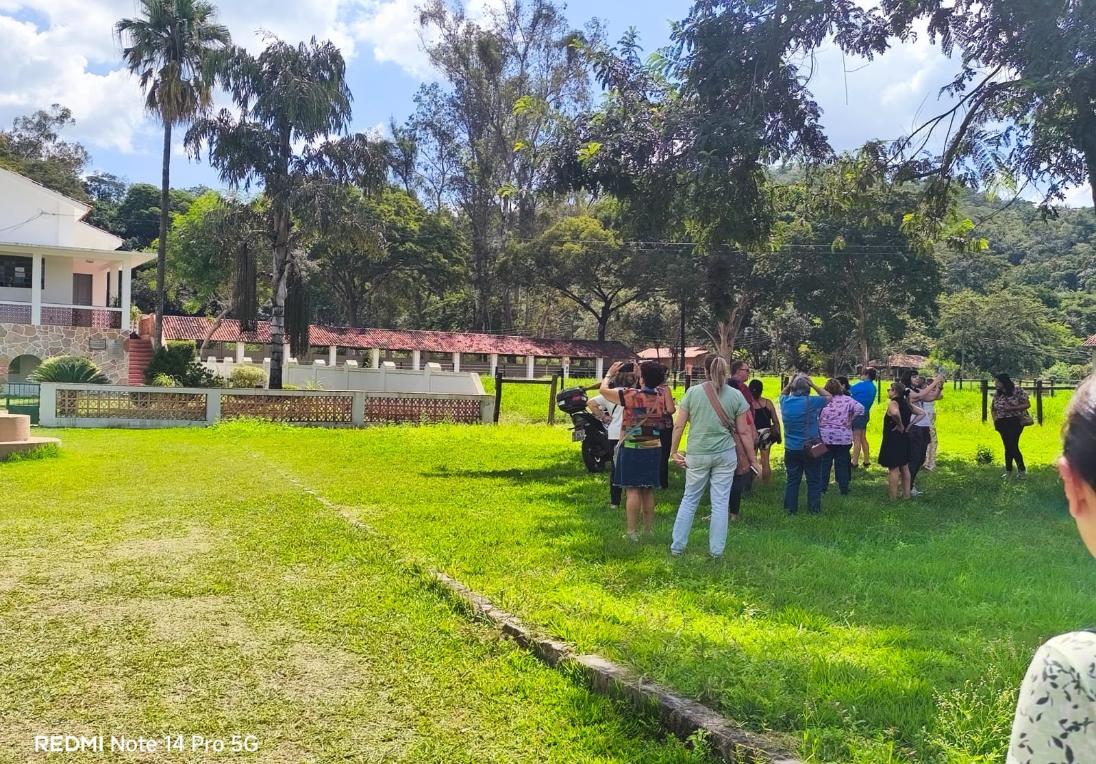Grupo grande em jardim ensolarado em frente a pousada histórica