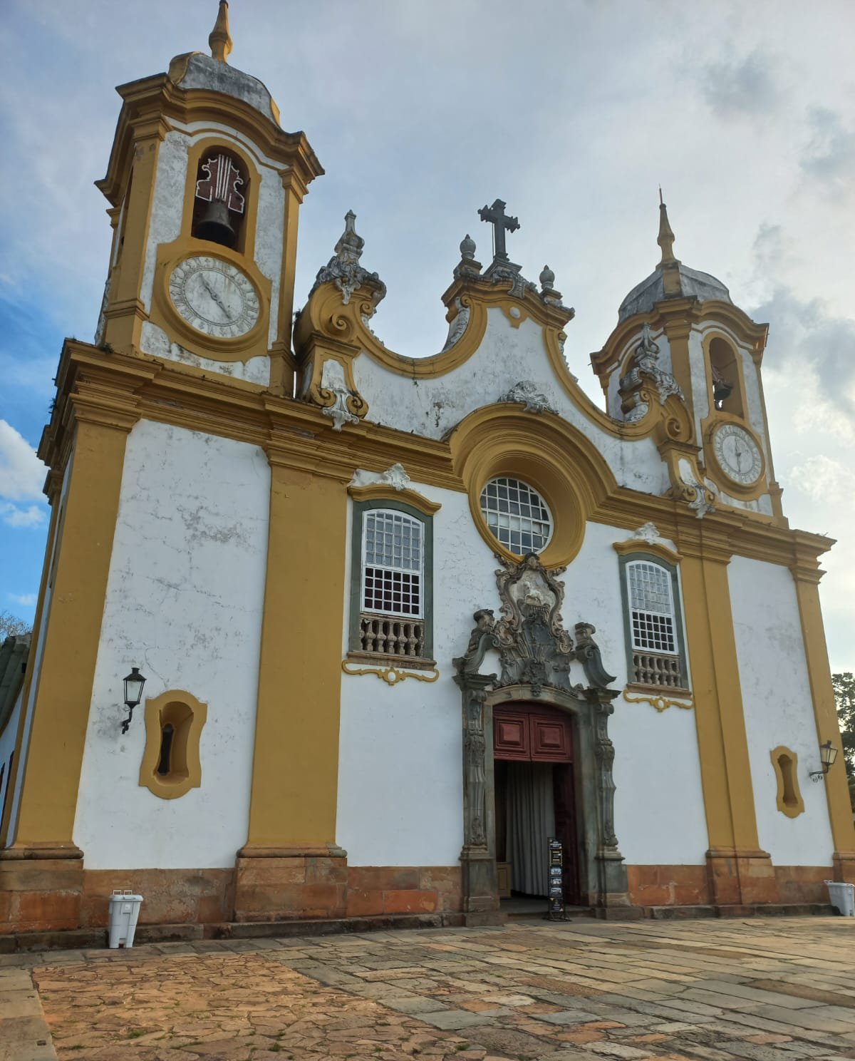 Fachada de Igreja histórica amarela com duas torres sob céu azul