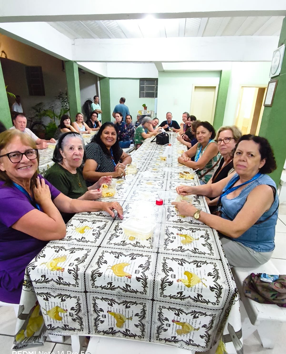 Grupo em sala de refeição comunitária ao redor de mesa longa