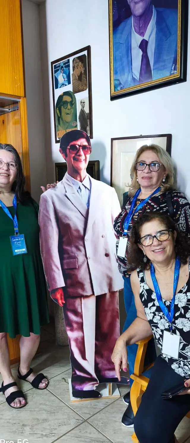 Grupo grande em interior decorado com fotos e quadros, pessoas contentes