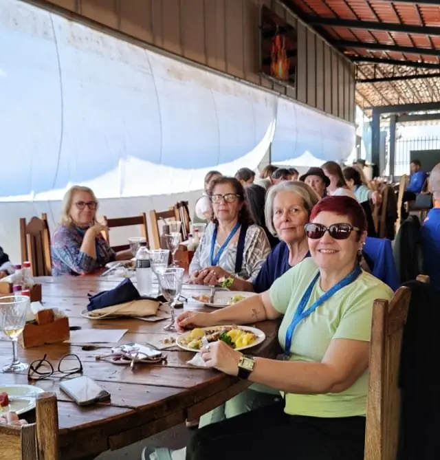 Mesa grande de refeição coletiva com grupo em ambiente de refeitório aconchegante
