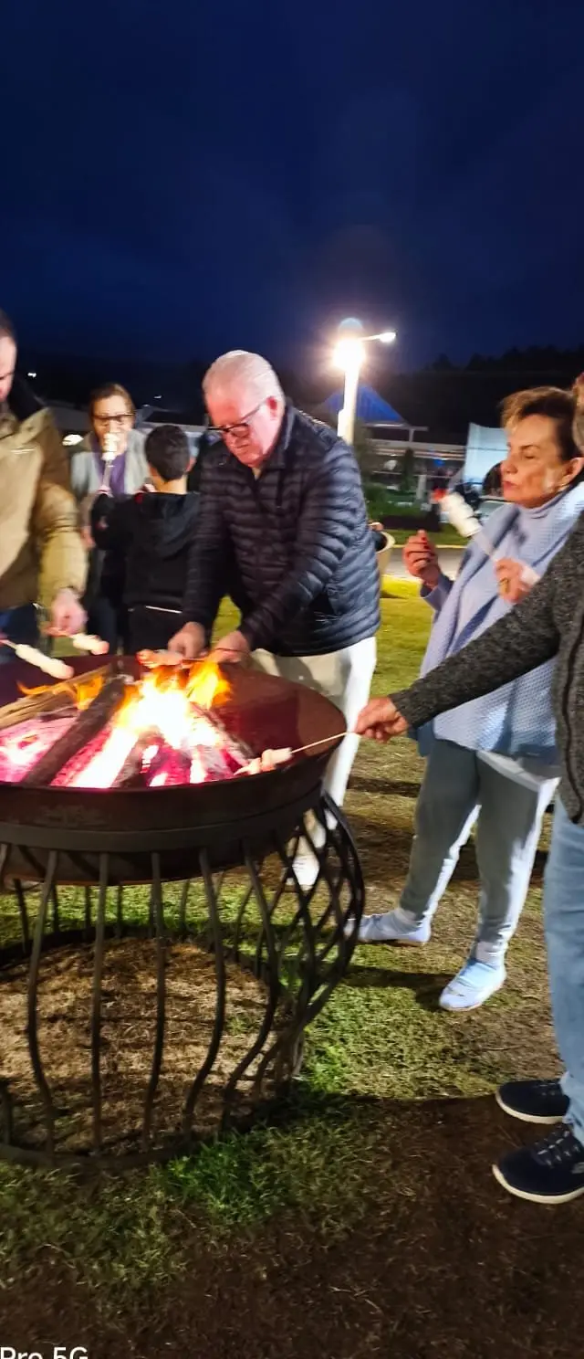 Grupo reunido ao redor de fogueira à noite, momento de celebração e confraternização