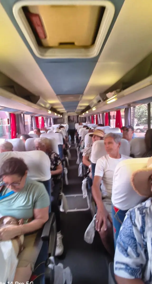Interior do ônibus com passageiros em assentos, grupo viajando, experiência de viagem