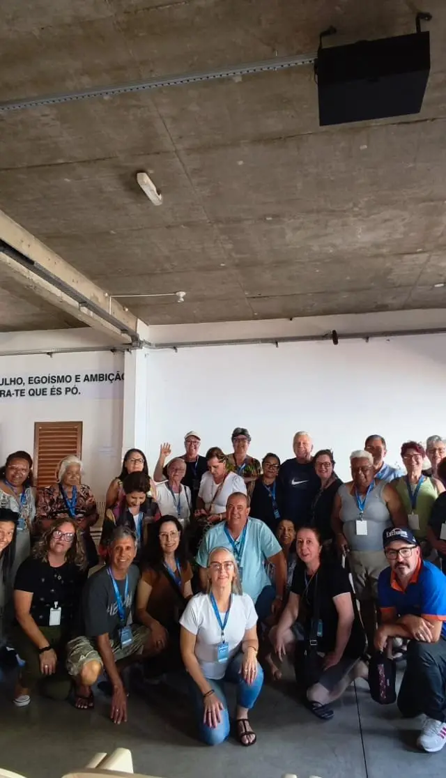 Grupo em evento interno, pessoas reunidas em espaço de apresentação, luz adequada