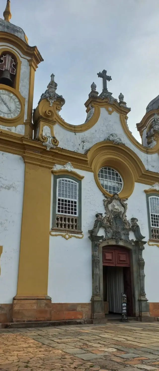 Fachada de Igreja histórica amarela com duas torres sob céu azul